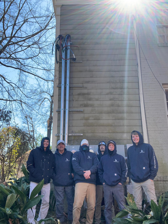 The Stroh Electrical team standing in front of an exterior electrical service installation on a building in Montgomery, AL.