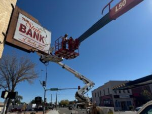 Electricians from Spectrum Lighting working on a large illuminated bank sign using a bucket lift in Colorado Springs, CO.