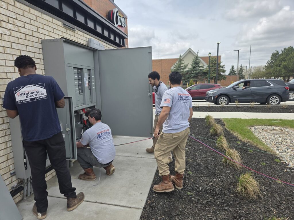 Multiple electricians from National Electric - Lansing working on a commercial electrical panel in Lansing, MI.