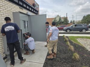Multiple electricians from National Electric - Lansing working on a commercial electrical panel in Lansing, MI.