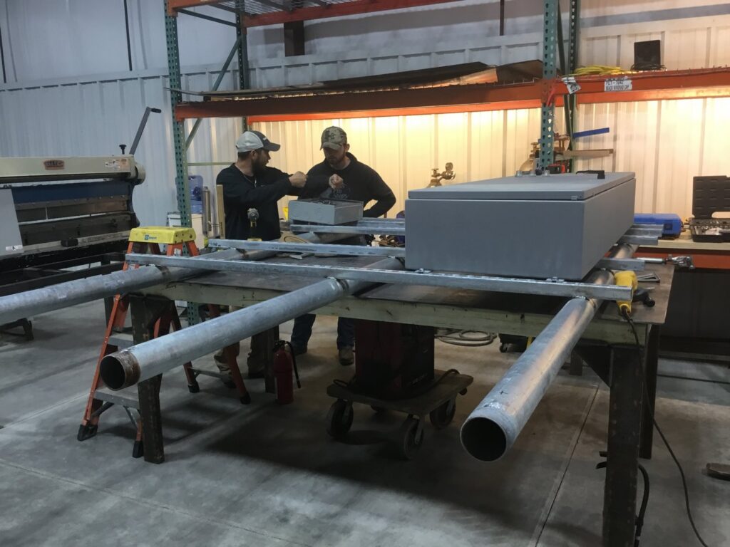 Two electricians working on electrical conduit and components in a workshop for Babcon Electric Inc. in Richmond, KY