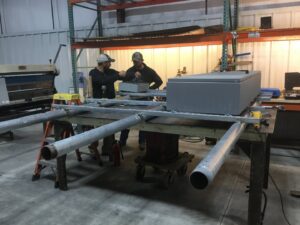 Two electricians working on electrical conduit and components in a workshop for Babcon Electric Inc. in Richmond, KY