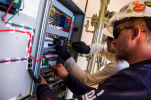 Two electricians from ITC Electrical Technologies working on an industrial electrical control panel in Casper, WY