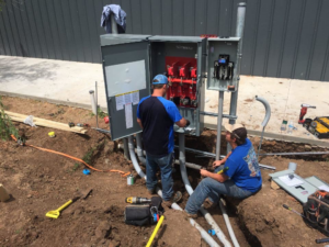 Two electricians from Enid Electric working on a main outdoor electrical panel installation in Enid, OK