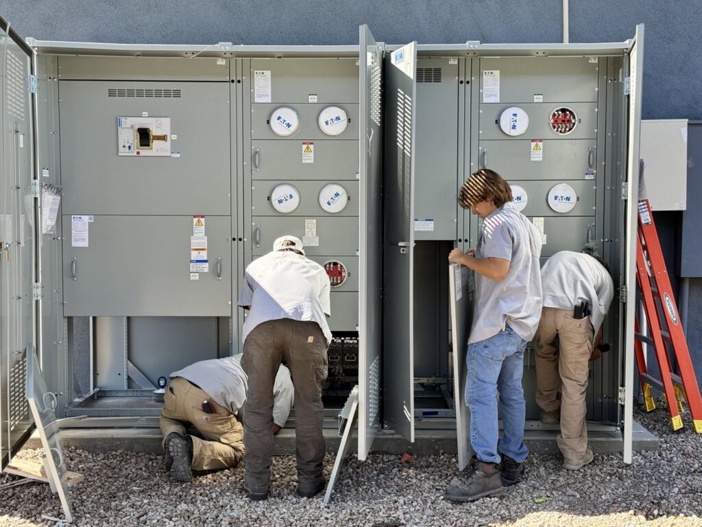 Electricians from TAP and Sons Electric working on large outdoor electrical meter banks in Tempe, AZ.