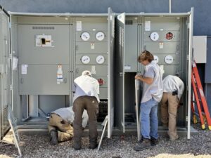Electricians from TAP and Sons Electric working on large outdoor electrical meter banks in Tempe, AZ.