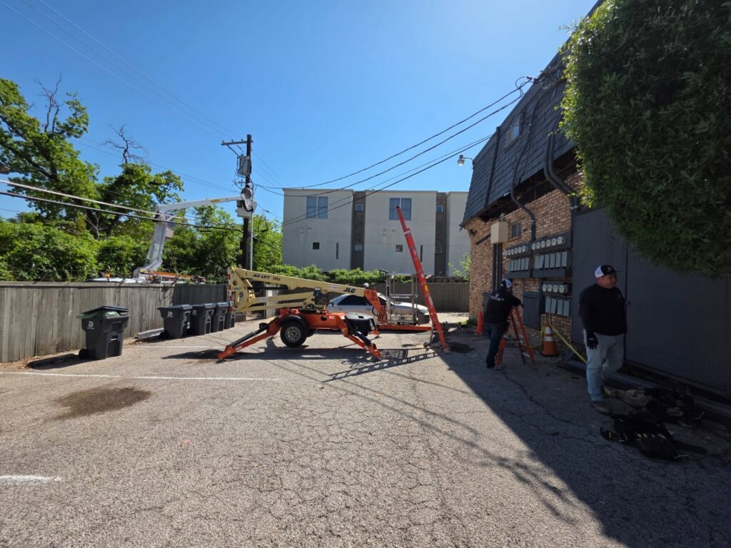 Electricians from Acevedo's Electric working on outdoor electrical lines and meters with a boom lift in Dallas, TX.