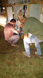 Two electricians working on an outdoor electrical panel at night for Genesys Electrical Contractors in Dallas, TX