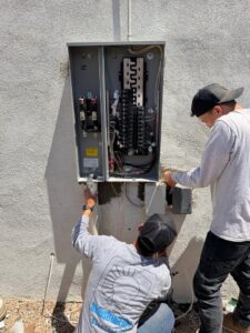 Two electricians working on an outdoor electrical service panel for Industrial Edge Electrical in Gilbert, AZ.