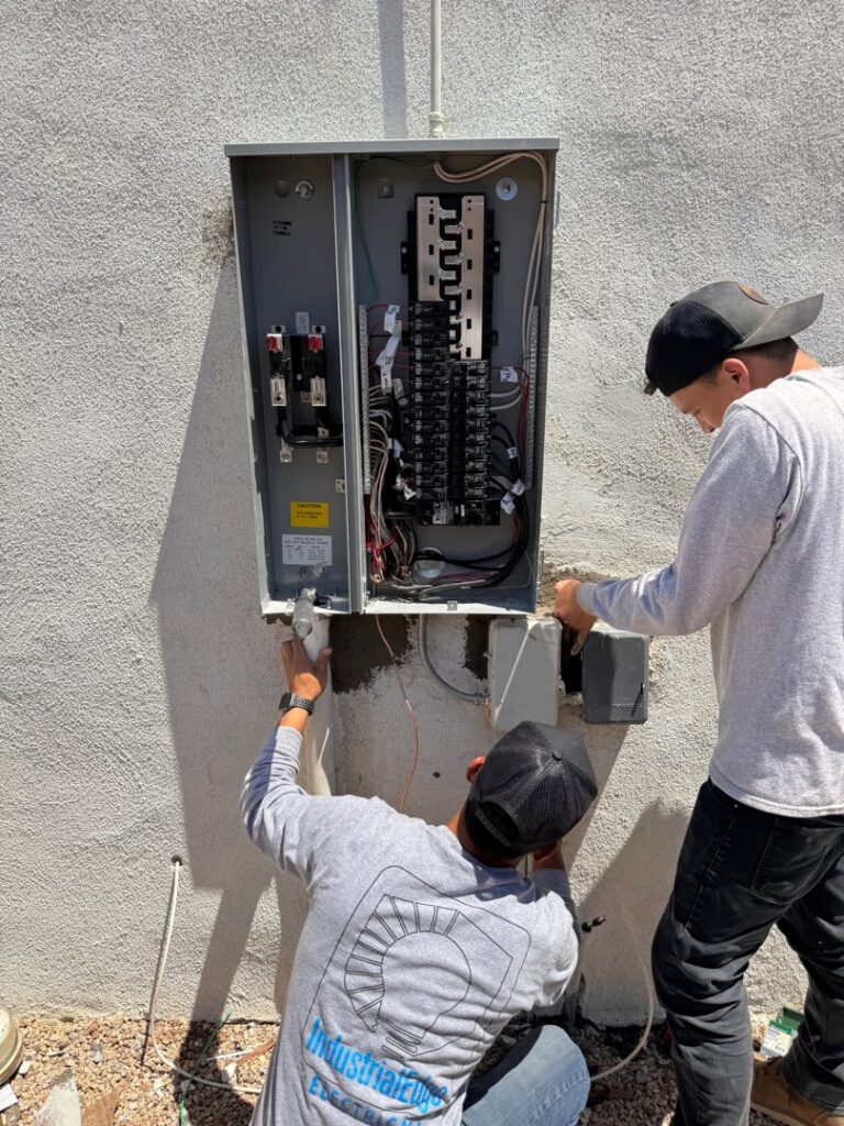 Two electricians working on an outdoor electrical service panel for Industrial Edge Electrical in Gilbert, AZ.