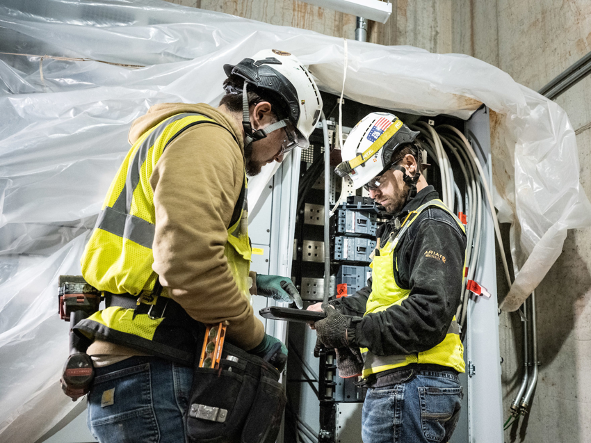 Two electricians working on an electrical panel at a job site for Encore Electric, Inc. in Lakewood, CO.