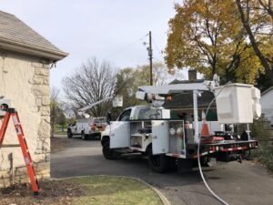 Electricians in bucket trucks working on power lines near a residential property for Buckeye Electric of Upper Arlington, LLC in Columbus, OH.