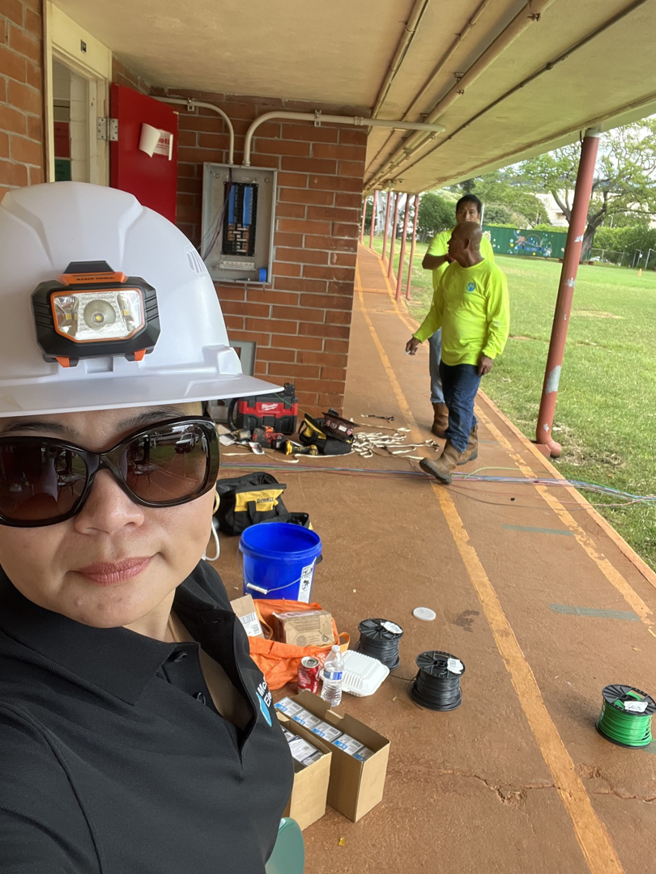 Electricians working on an outdoor electrical installation with tools and wiring, captured by Mcdaniel Electric, LLC in Waipahu, HI.