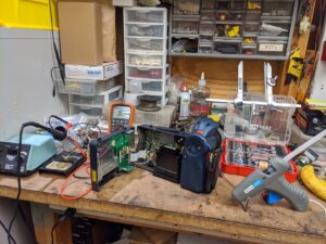A workbench with electronics repair tools and components, including a multimeter, at J&L Electric Inc. in San Antonio, TX