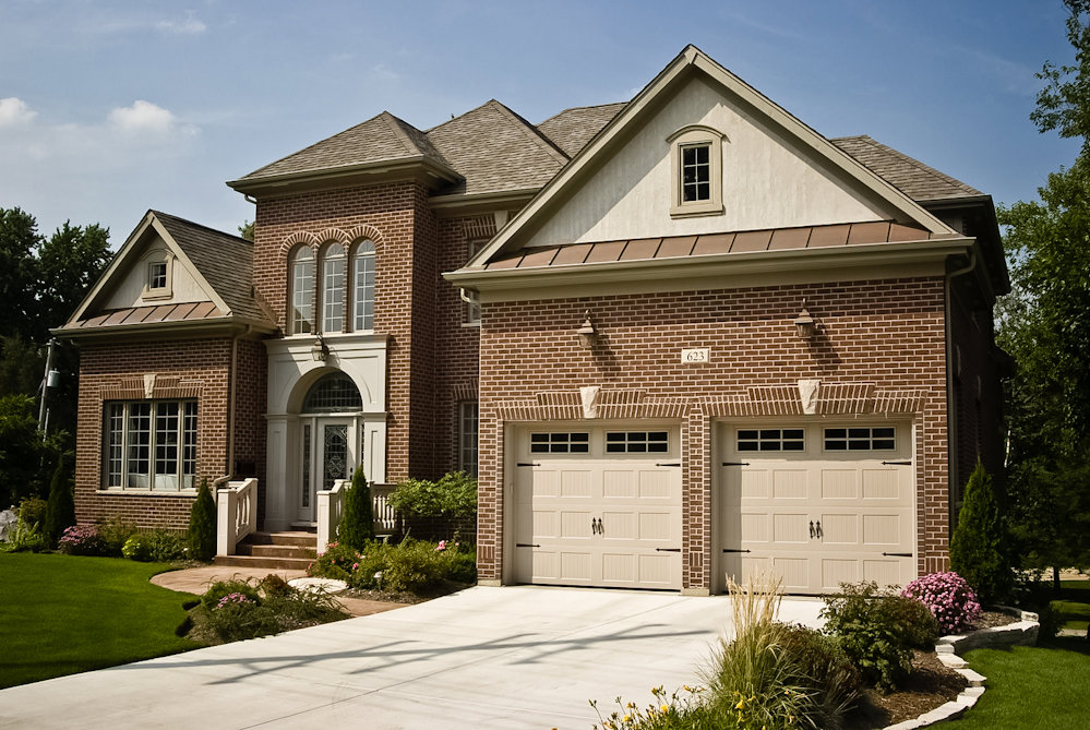 An elegant brick house showcasing two newly installed garage doors by Precision Garage Door of Charleston in North Charleston, SC.