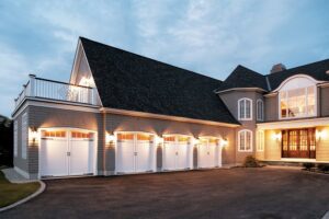 An elegant home showcasing four white garage doors with windows, installed by Overhead Door Company of Central Missouri in Columbia, MO.