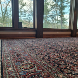 An elegant oriental rug laid over a hardwood floor in a bright room, showcasing work by Borokhim's Oriental Rugs in Madison, WI.