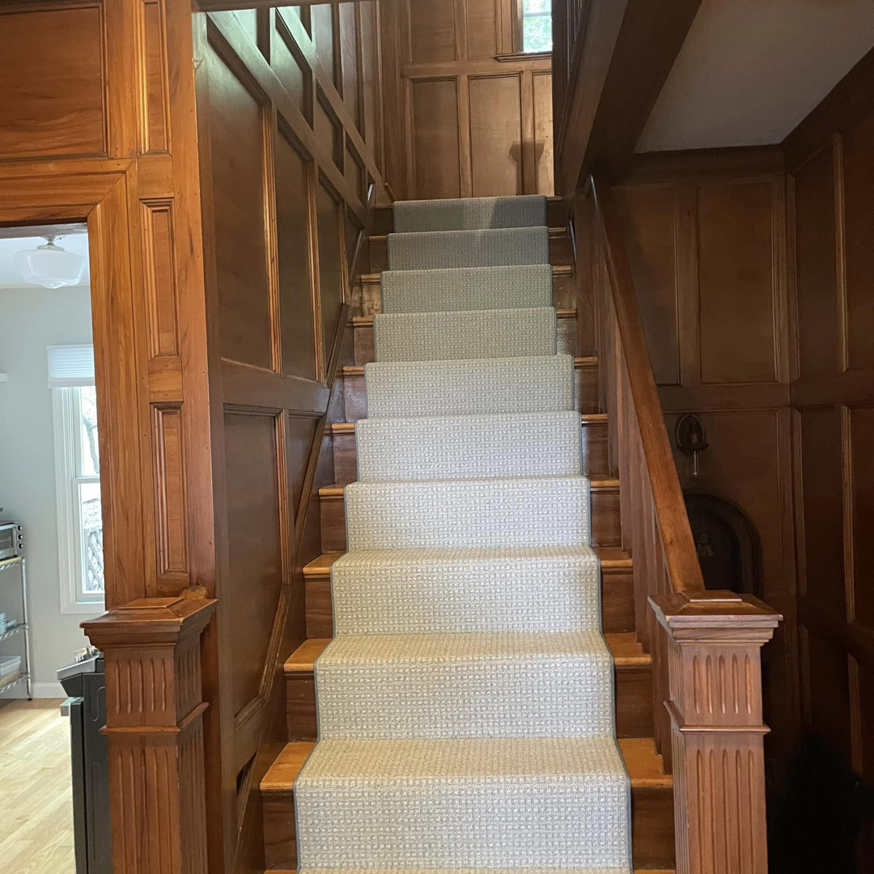 An elegant carpet runner professionally installed on a wooden staircase by J MIKE PONTE FLOOR COVERING in Lowell, MA.