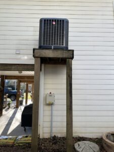 An outdoor HVAC unit installed on an elevated wooden platform by Budget Heating and Air in Mobile, AL.