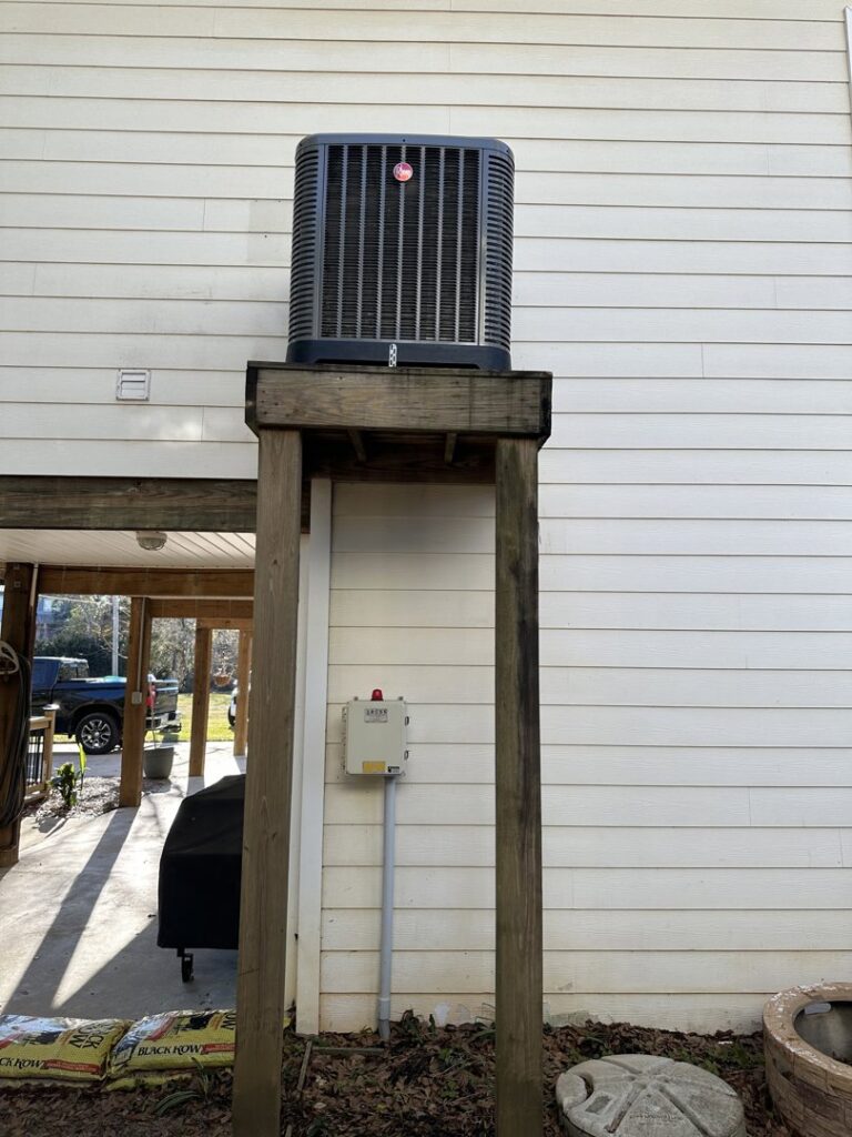 An outdoor HVAC unit installed on an elevated wooden platform by Budget Heating and Air in Mobile, AL.