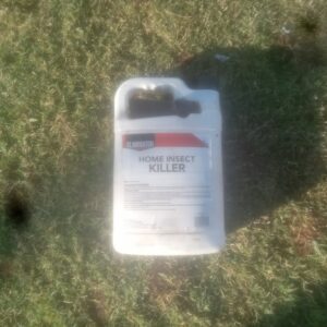 A bottle of Eliminator Home Insect Killer on a lawn, indicating pest control services by A & A Lawn Care Service LLC in Edmond, OK.