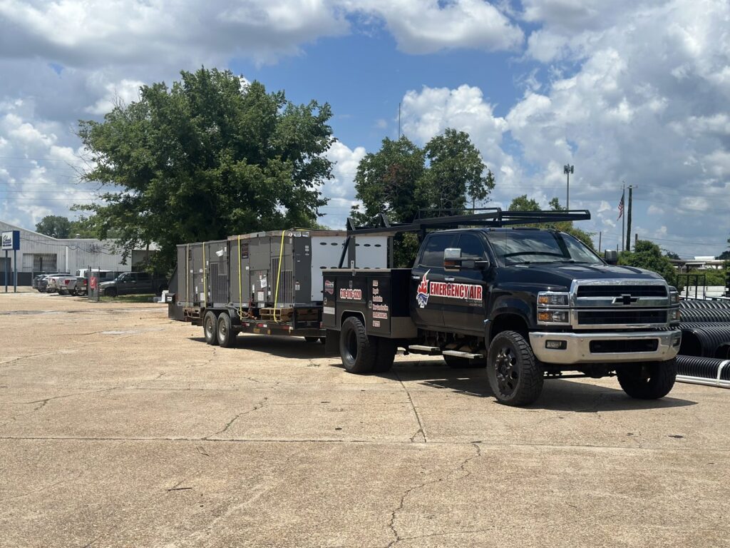 An Emergency Air branded truck and trailer transporting large HVAC units for a job in Chandler, AZ.