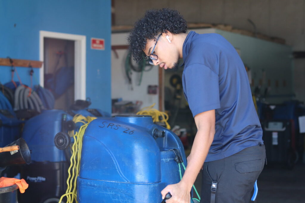 An employee moving a large carpet extractor machine for a job by Strategic Carpet Clean in Winter Park, Orlando, FL