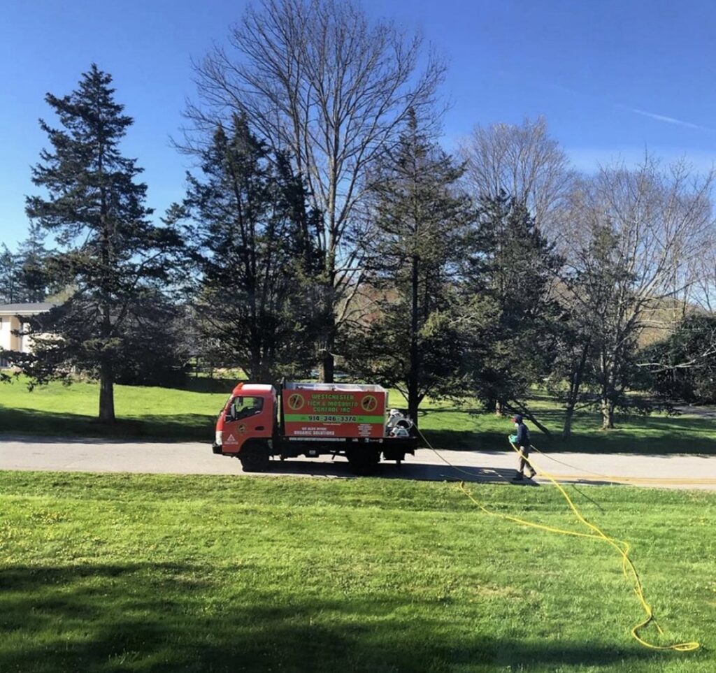 An employee from Westchester Tick and Mosquito Control deploying a hose for pest control services in New Rochelle, NY.
