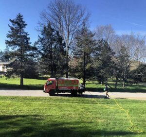 An employee from Westchester Tick and Mosquito Control deploying a hose for pest control services in New Rochelle, NY.