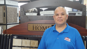 An employee standing in front of various carpet samples at JCB Interiors in Stamford, CT