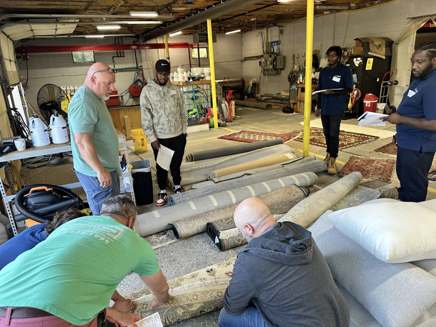 Employees inspecting rolled oriental rugs in a workshop at Thomas Carpet & Oriental Rug Cleaners in Newtown Square, PA