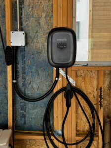 An Emporia EV charger professionally installed on a wooden wall by ChargerPro in Denver, CO.