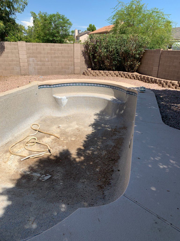 An empty and dirty swimming pool, indicating a need for renovation or cleaning services from East Mesa Pools, LLC in Mesa, AZ.