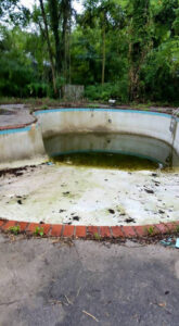 An empty, dirty pool with green residue and debris, ready for deep cleaning by A-Grade Pools in Knoxville, TN.