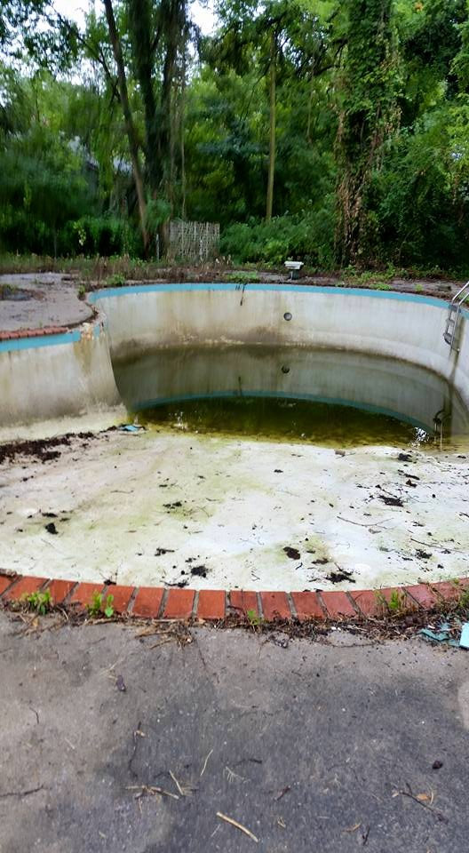 An empty, dirty pool with green residue and debris, ready for deep cleaning by A-Grade Pools in Knoxville, TN.