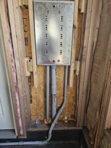 An empty electrical panel box with conduits during rough-in wiring in new construction by Titus & Son's Electric in Bluffton, IN.