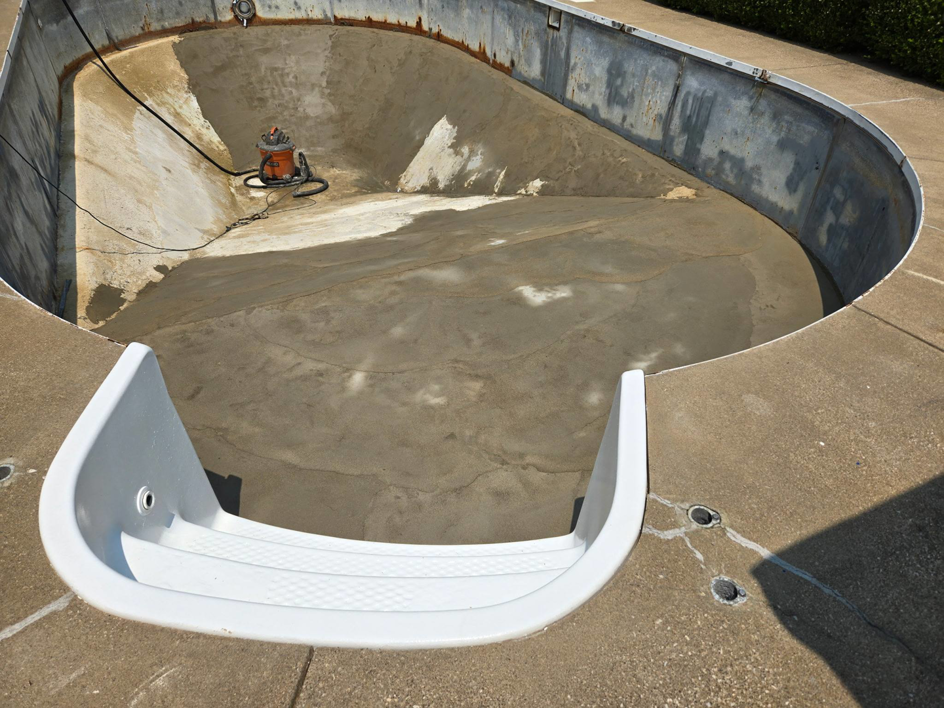 An empty inground pool shell with concrete work in progress, preparing for a new liner installation by Westside Pools in Owensboro, KY.