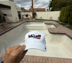 An empty swimming pool undergoing renovation, with a contractor's hat in view, by All Valley Pools in Avondale, AZ.
