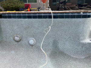 An empty swimming pool with a hose inside, indicating draining or deep cleaning services by Aquatec Pool Care in Jacksonville, FL.