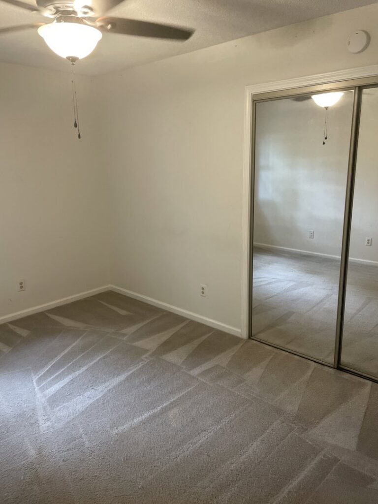 An empty room with a freshly cleaned carpet showing vacuum lines by Wilmington Carpet Cleaning NC in Wilmington, NC.