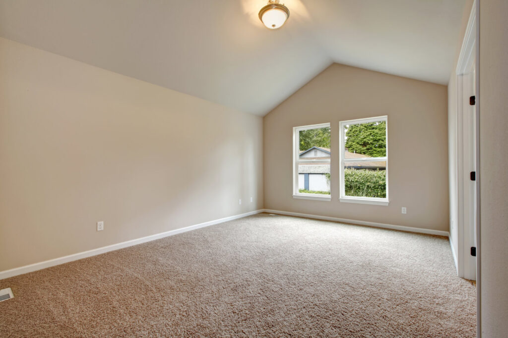 An empty room showcasing new light brown wall-to-wall carpet, a service provided by United Carpet in Rochester, NY.