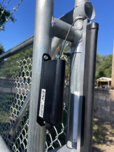 An EMX gate safety sensor installed on a chain-link gate post by Brothers Gate Operators and Services LLC in Olathe, KS.