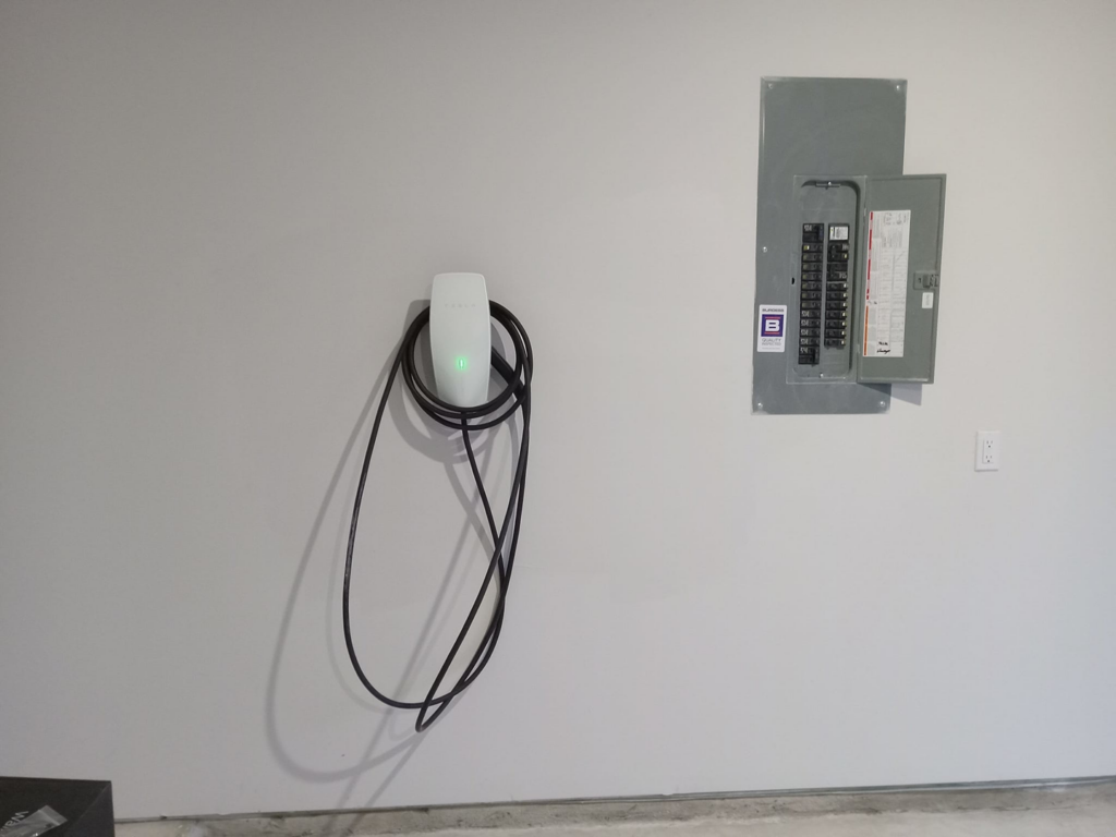 An installed EV charger and open electrical panel in a garage by Valle Home Maintenance in Houston, TX