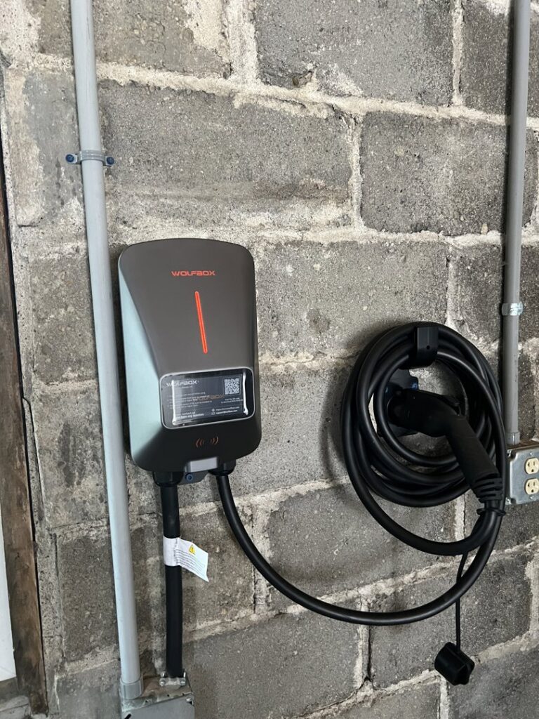An EV charger installed on a concrete block wall with electrical conduit by Three Rivers Electric in Fort Wayne, IN.