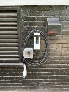 An EV charger professionally installed on an exterior brick wall by Copper And Current Electrical Services in Greensboro, NC.