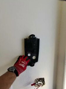 An electrician's gloved hand working on an EV charger installation, showing wires, by Big Red Electric Company in San Antonio, TX.