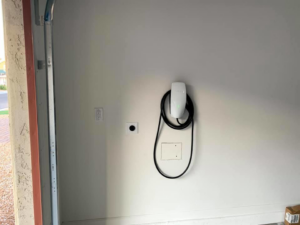 An installed Tesla EV charger and electrical outlet on a garage wall by R&M Electric LLC in Gilbert, AZ.