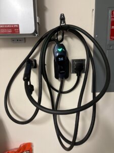 A wall-mounted EV charger installation with its coiled cable, completed by Muse Electricians in Los Angeles, CA.