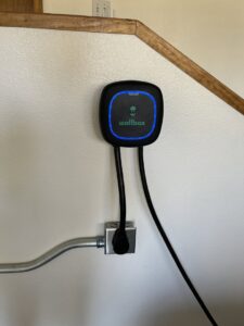 A Wallbox EV charger installed on a wall with electrical conduit and outlet by Mountain Electric in Knoxville, TN.