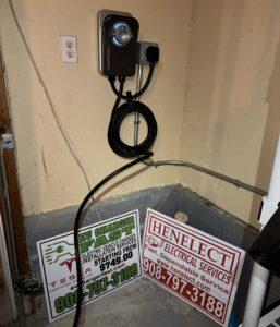 An EV charger installation with Henelect Electrical Contractors business signs in Milford, NJ.